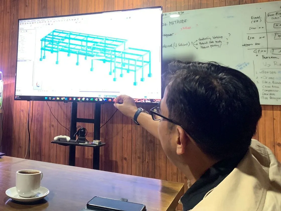 Anggota tim memaparkan model struktur bangunan di layar sebelum pekerjaan dimulai